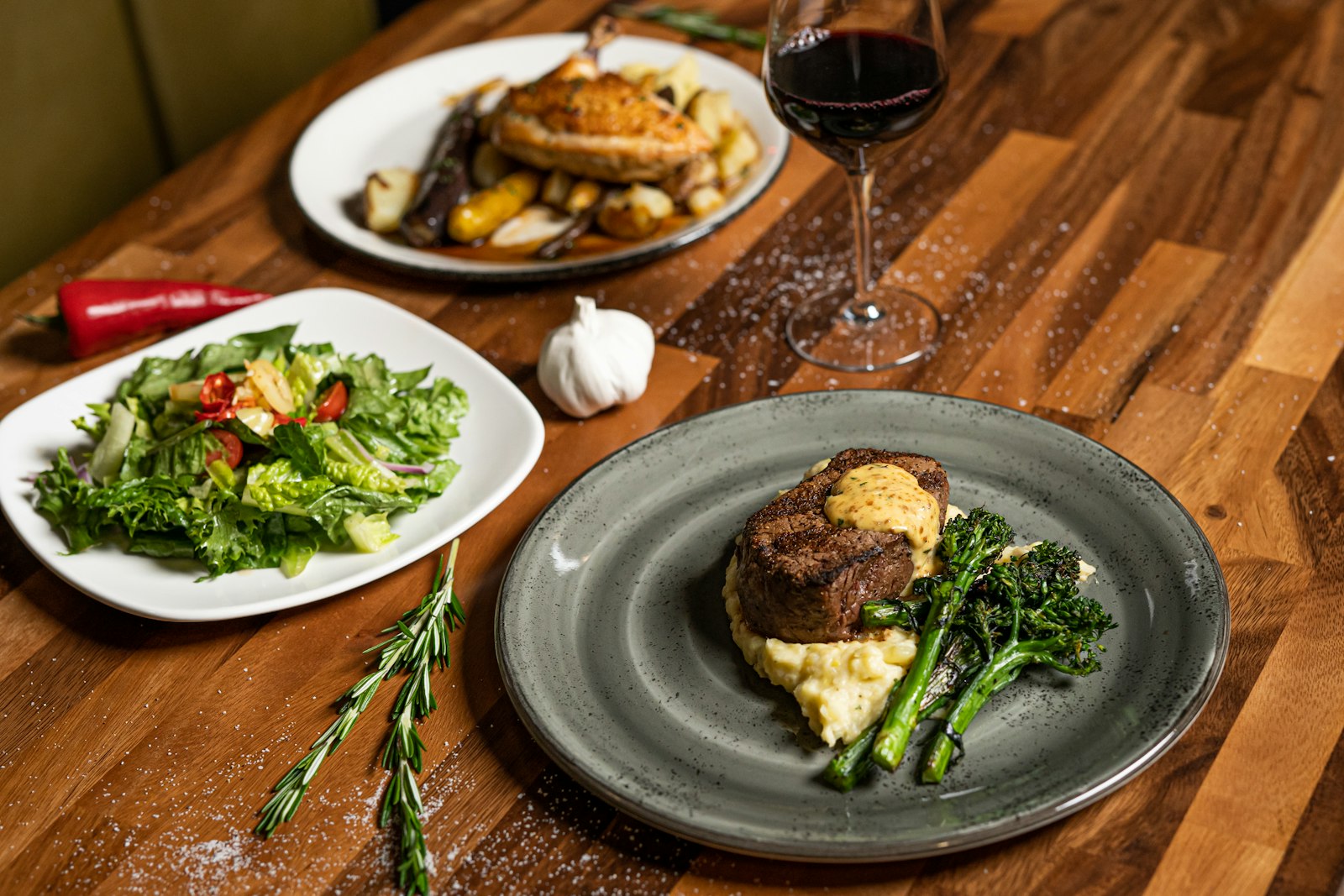 A plated steak dinner with roasted vegetables and a glass of red wine